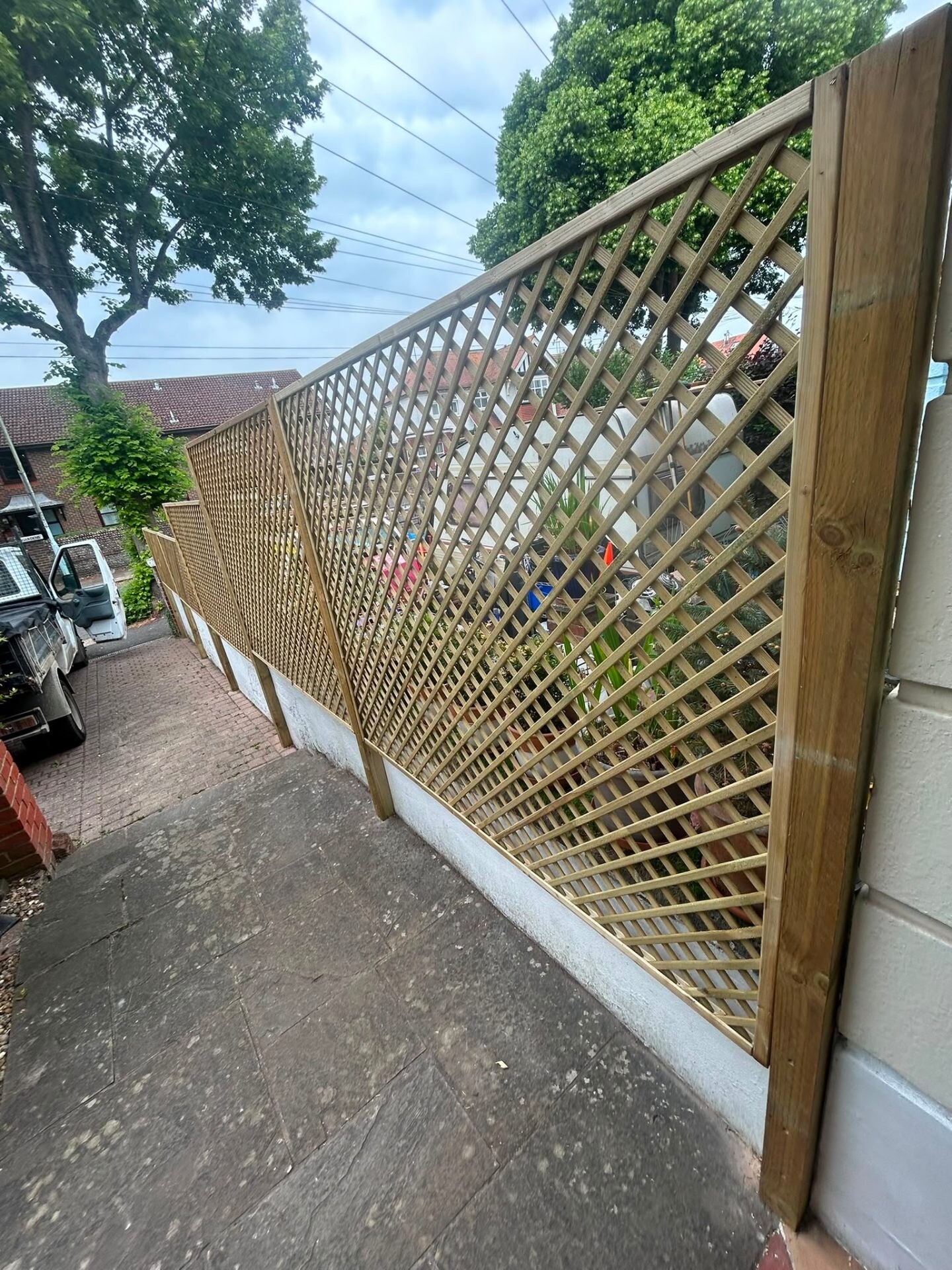 Closeboard fence with diamond trellis topper installed in a back garden in West Sussex.