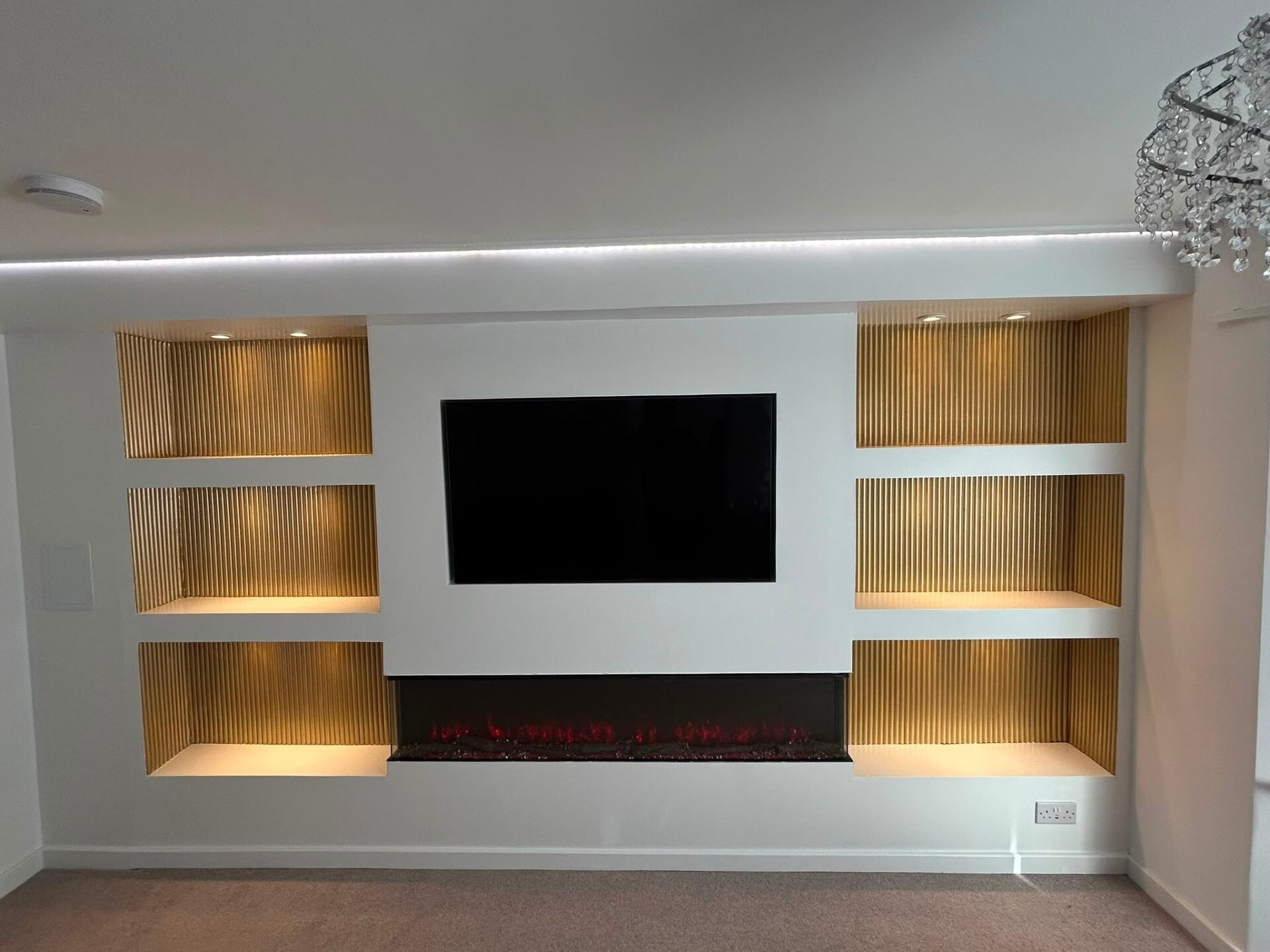 Modern white media wall with reeded oak shelves and recessed lighting.
