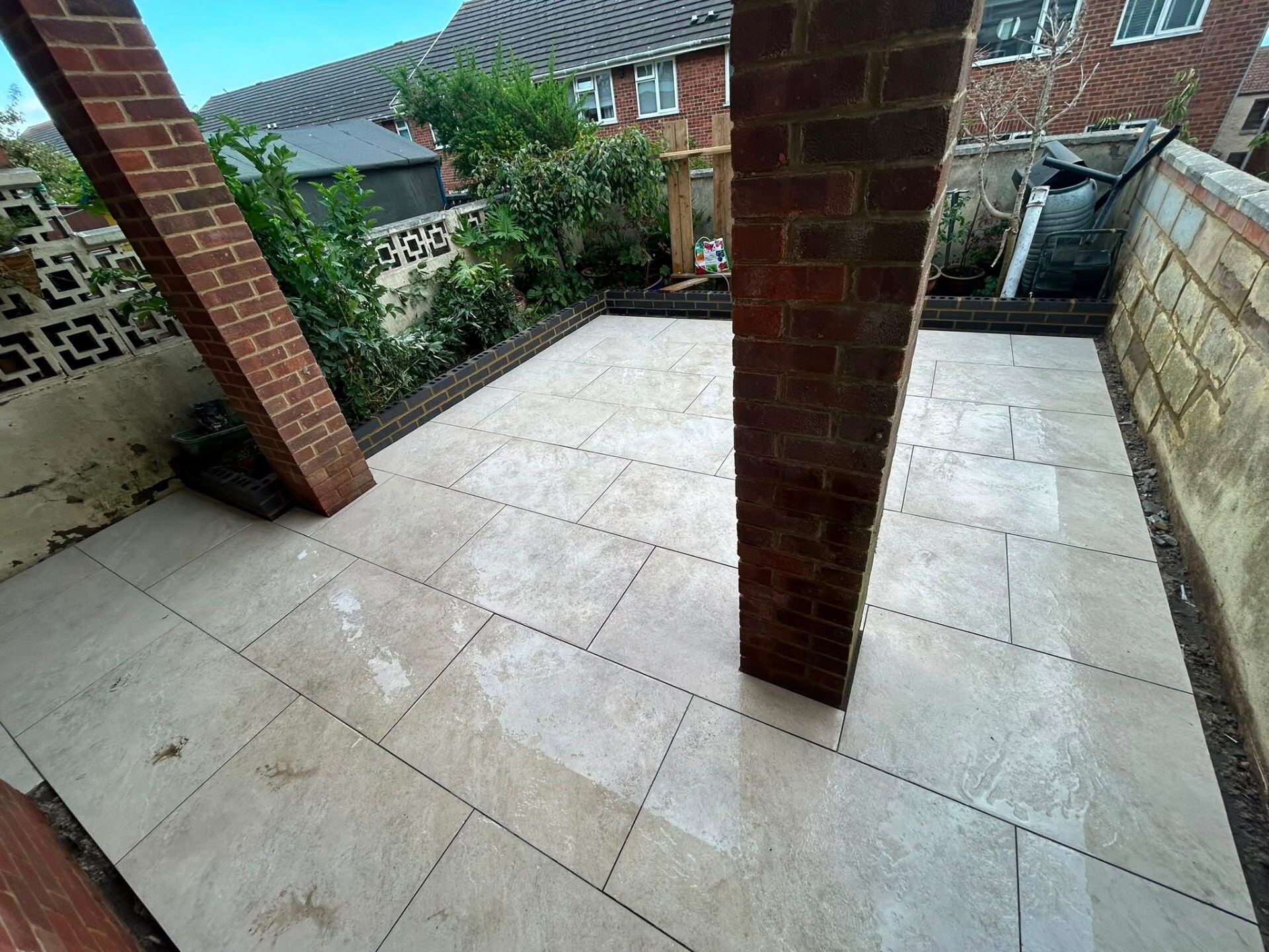 Polished porcelain patio with original brick pillars retained on a Sussex property.