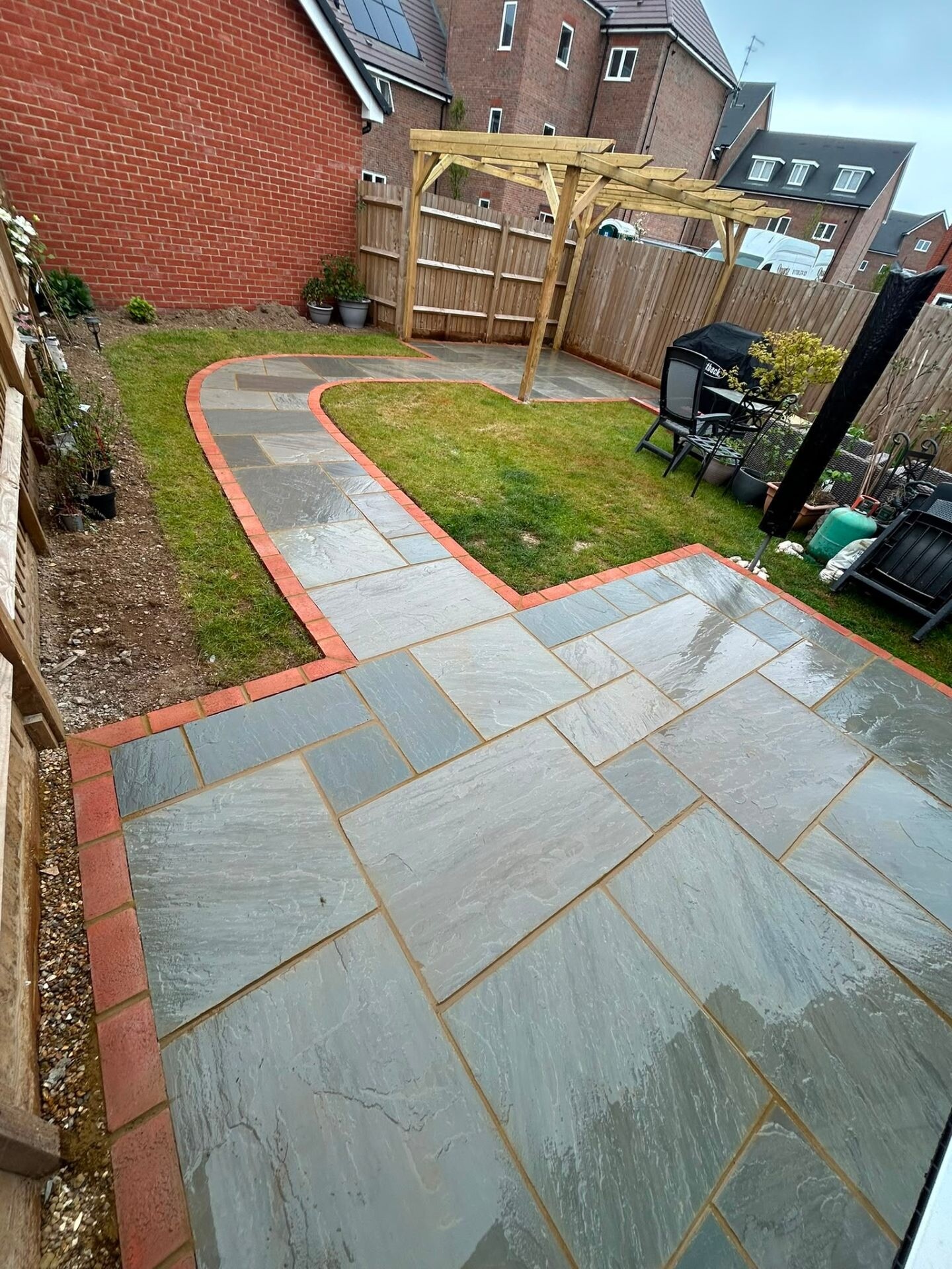 Riven sandstone path with red-brick edging leading to a timber pergola.