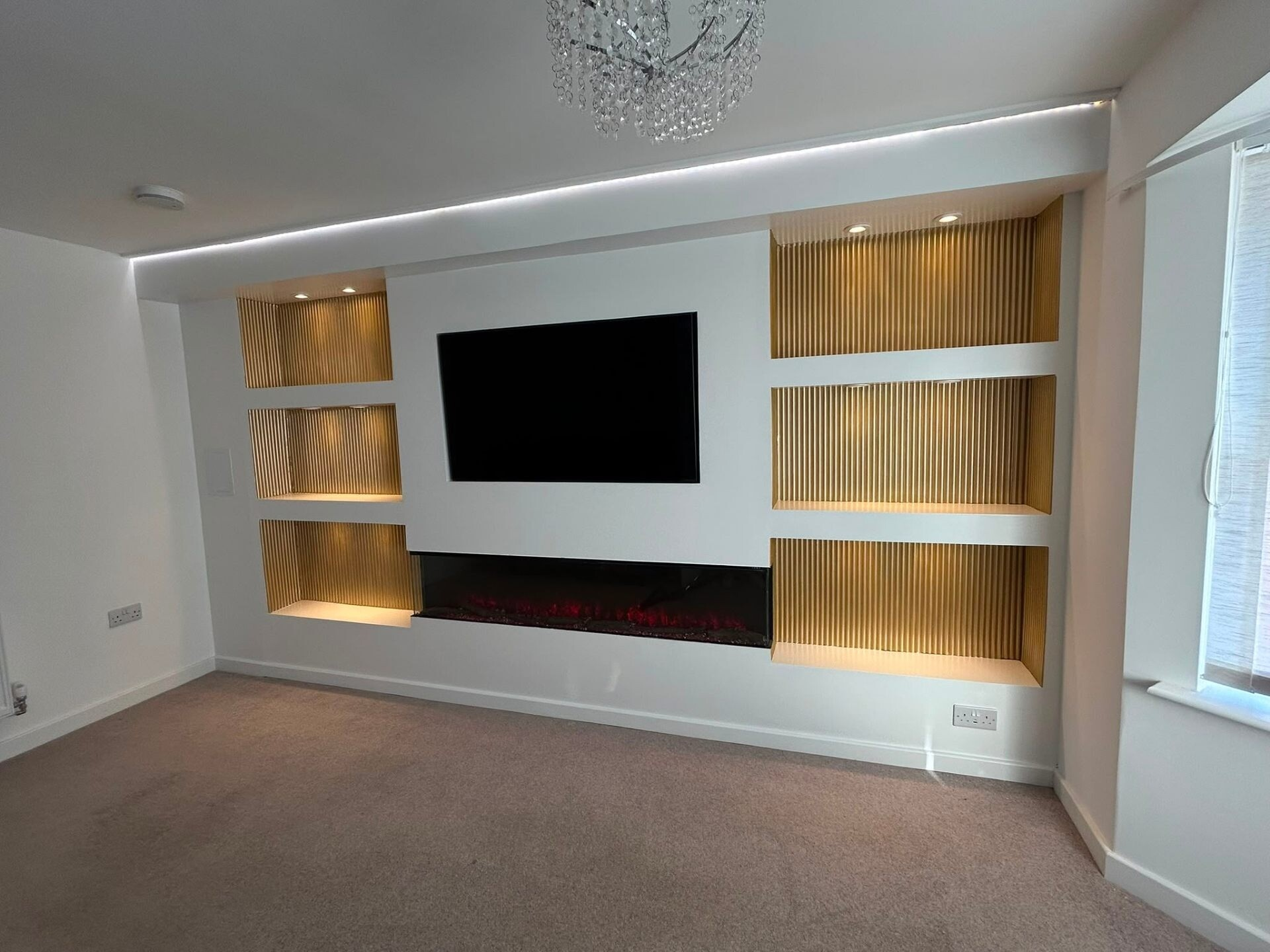 Bespoke white media wall with reeded oak inserts, integrated LED lighting and inset electric fire — installed by Heavens Property Solutions.