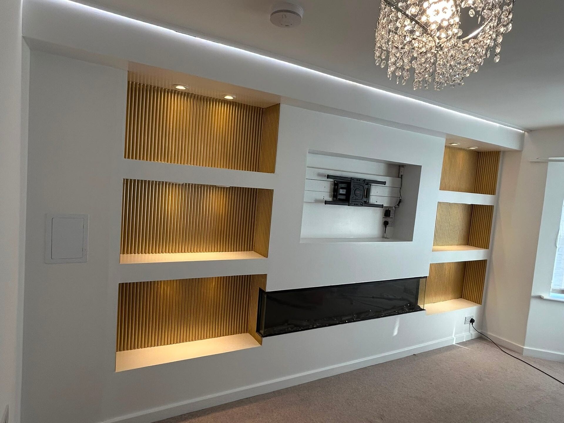 Premium white media wall with reeded oak inserts and crystal pendant lighting.