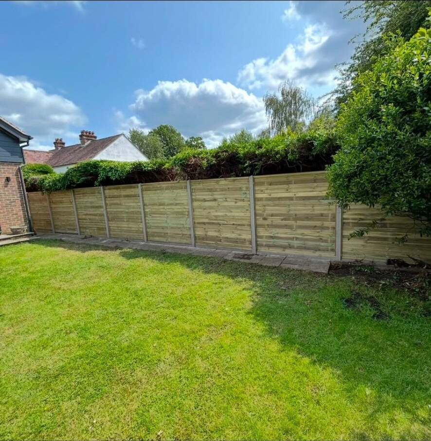 Front-garden artificial lawn laid against a low timber edge.
