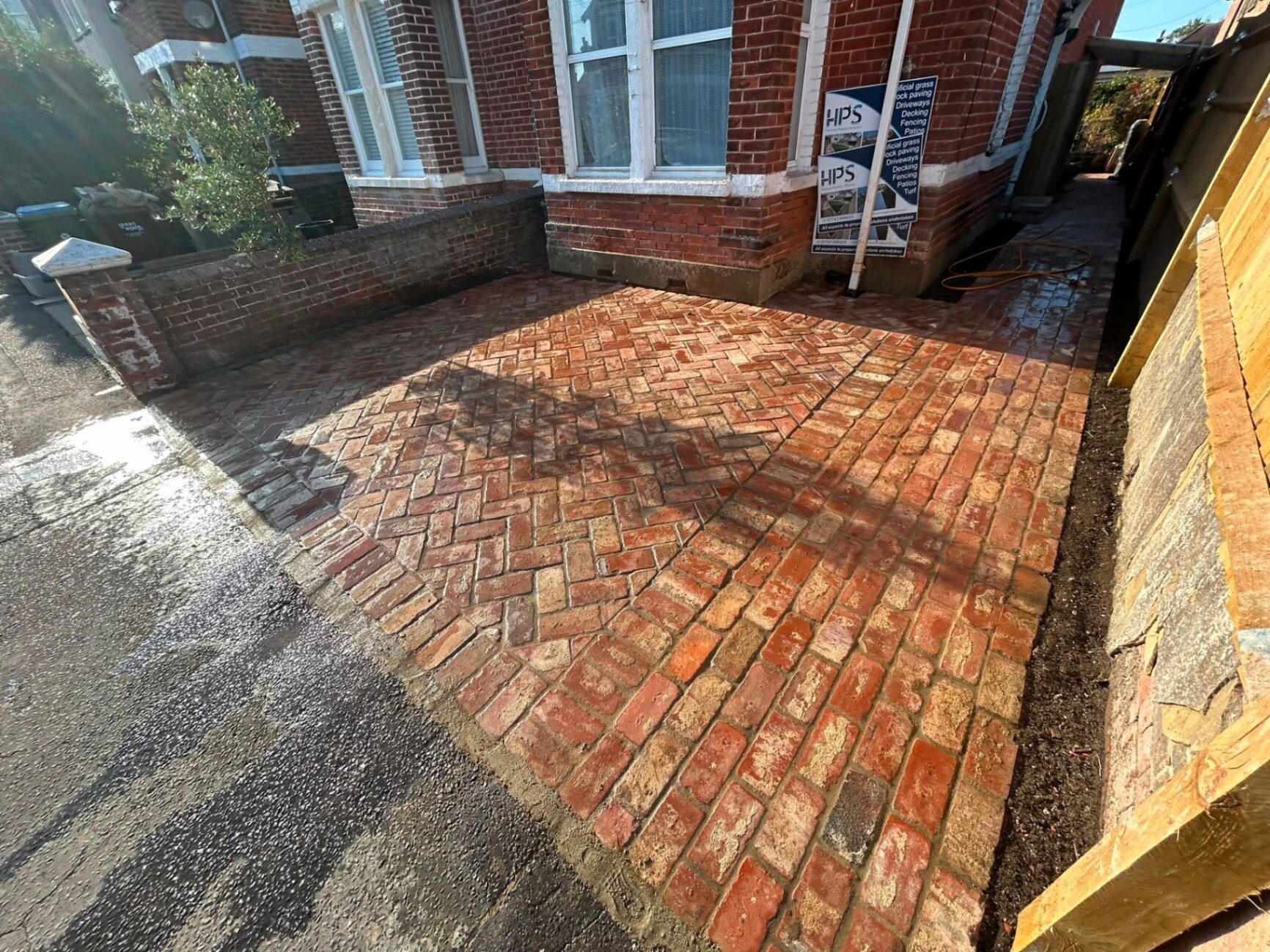 Red clay-brick paving being laid in a herringbone pattern on a freshly bedded sub-base.