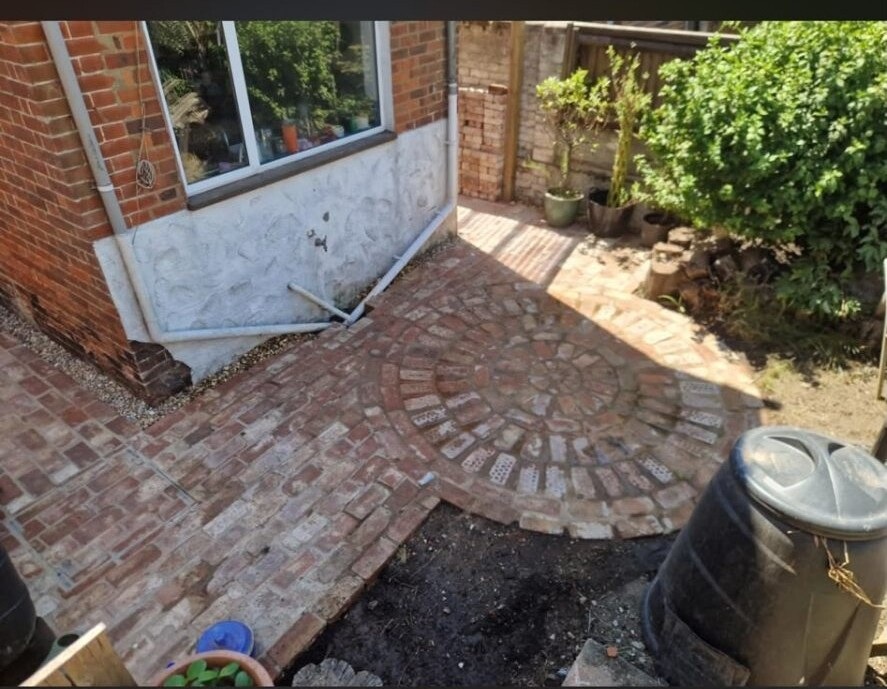 Red clay-brick patio area with crisp jointing and timber raised beds.