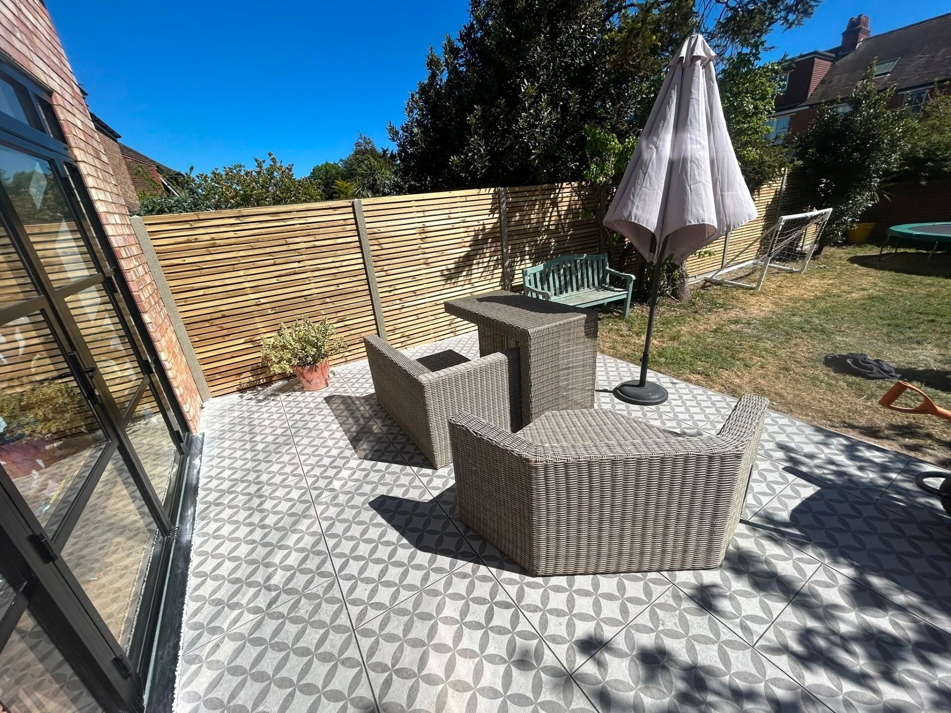 Porcelain patio styled with rattan furniture and a parasol for outdoor dining.