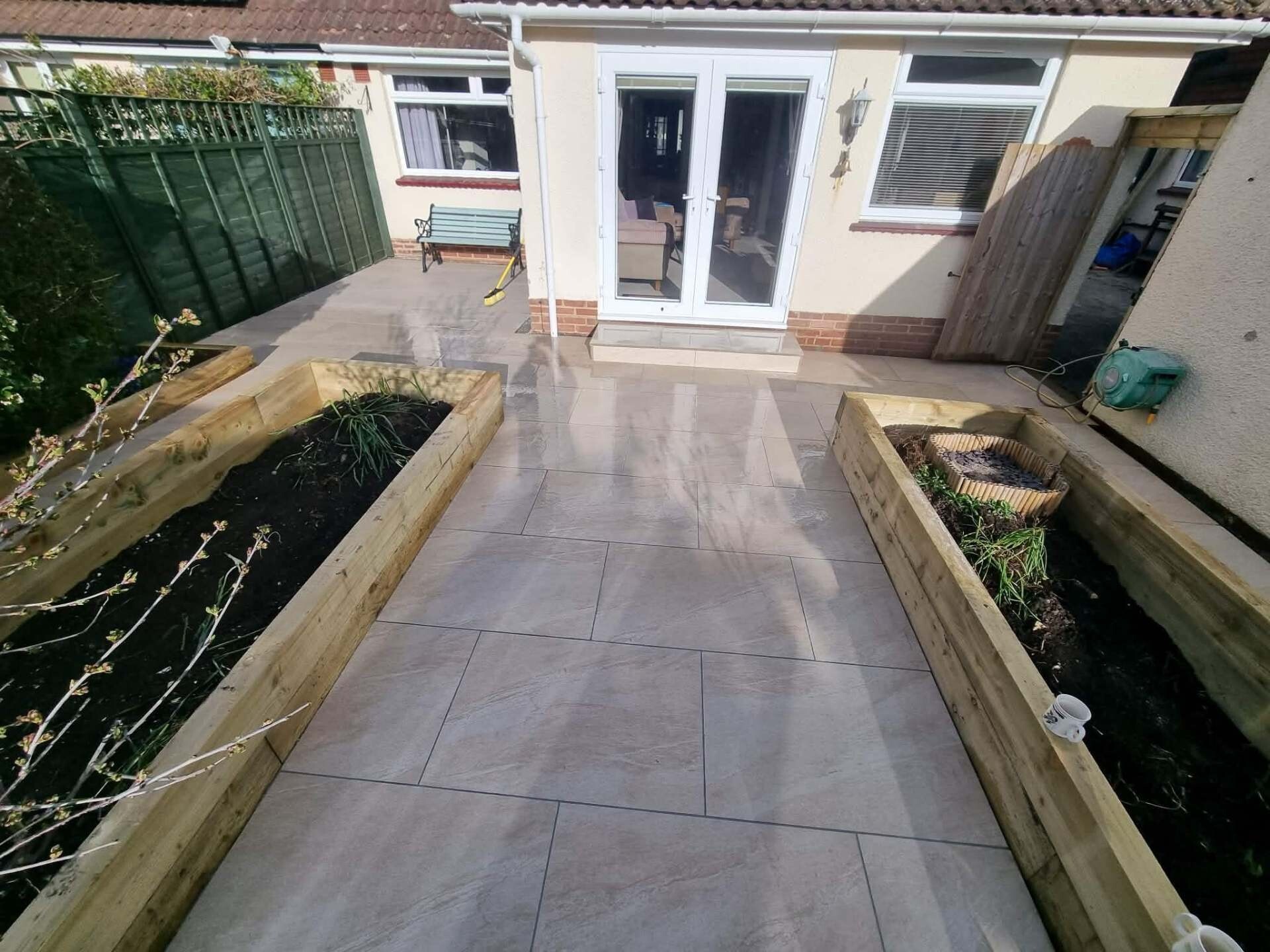 Sandstone patio with timber raised beds at the rear of a Littlehampton home.