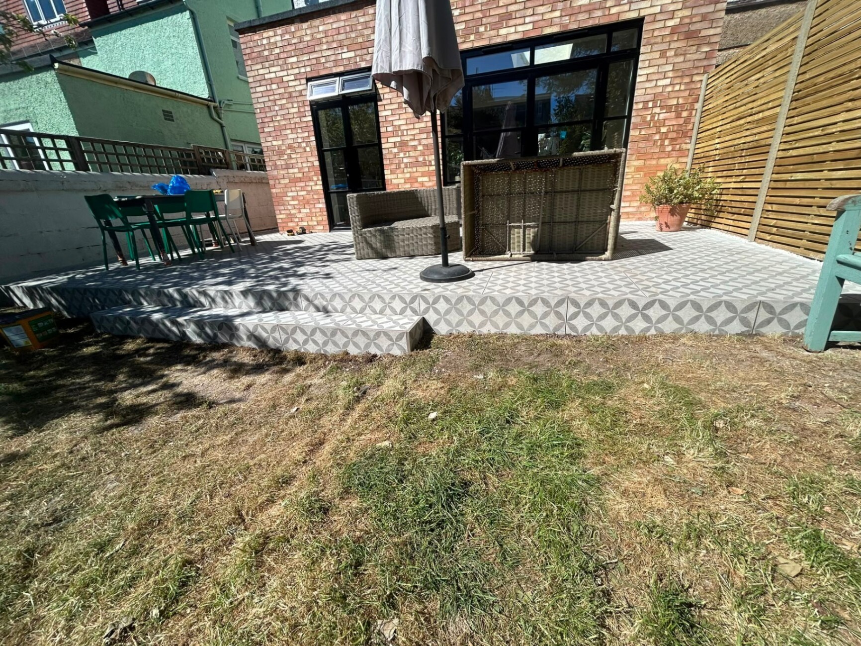Porcelain patio and steps leading down to the lawn in a redesigned back garden.